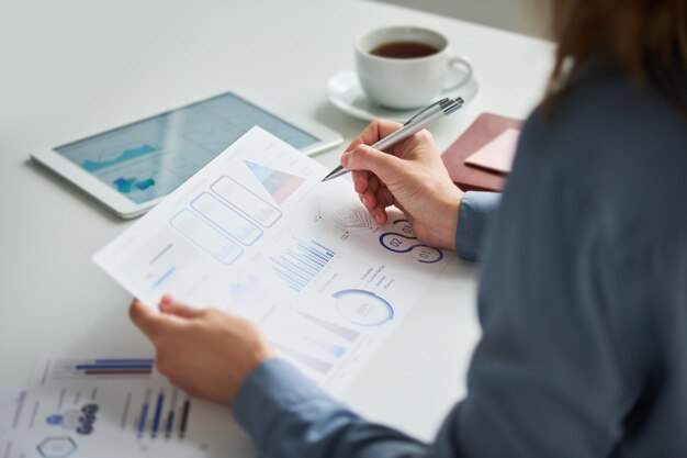 Photo focus on hand of young female accountant or auditor holding pen