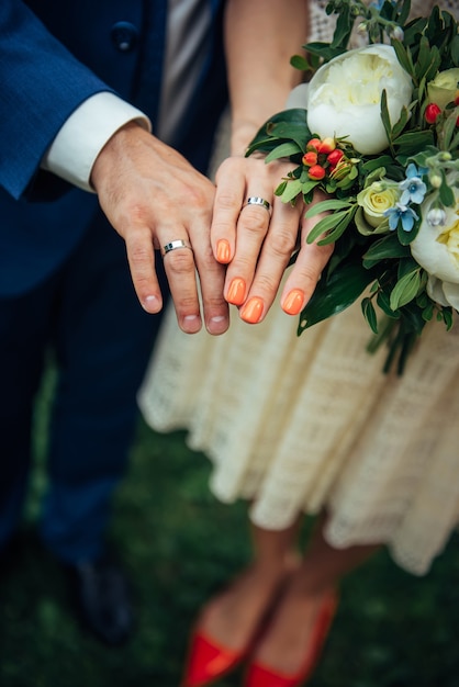 Focus on the hands of bride and groom, wedding bouquet