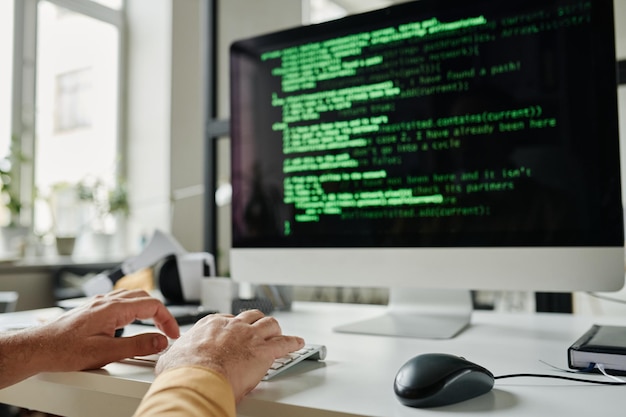 Focus on hands of mature programmer typing on keyboard