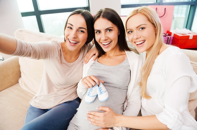 focus on happiness. top view of happy young pregnant woman holding baby booties on her abdomen 