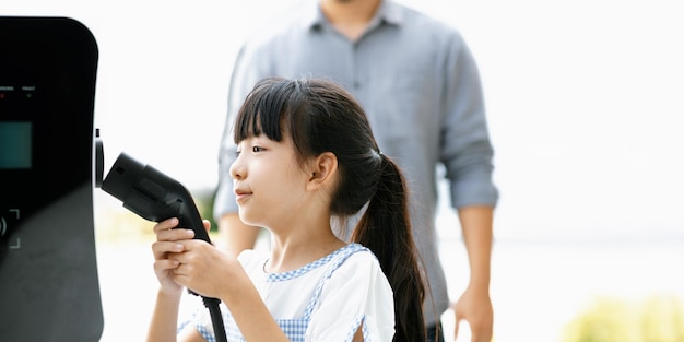 Focus image of progressive young girl holding EV charger device