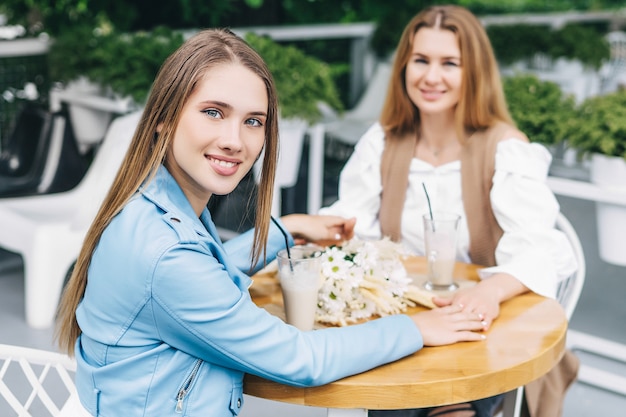 Il focus è su una bella ragazza che sorride e guarda la telecamera e tiene la mano di sua madre