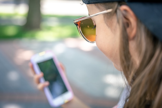 Il focus è sugli occhiali da sole sul viso della ragazza che guarda il telefono.