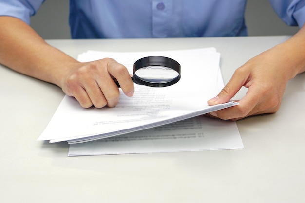 Focus magnifying glass Hand of businessperson looking at documents through magnifying glass