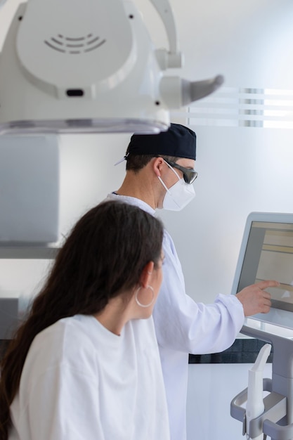 Focus on male dentist touching a screen while his female patient is waiting for him Dental clinic concept