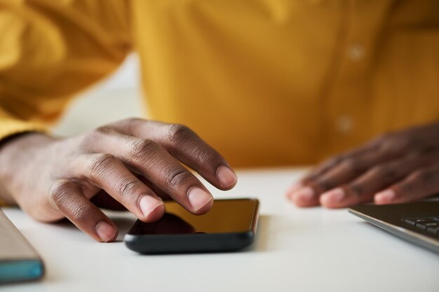 Focus op de vingers van de rechterhand van jonge mannelijke kantoormedewerker via smartphone