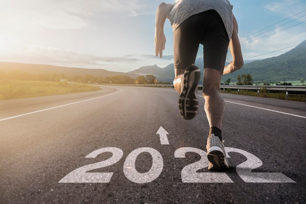 Foto focus op de voeten van een hardloper die loopt op een weg gemarkeerd 2022. begin en begin van het nieuwe jaar 2022, doelen en plannen voor het volgende jaar. gelukkig nieuwjaar 2022.