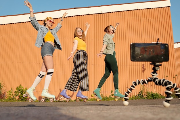 Focus op drie gelukkige jonge vrouwelijke rolschaatsers die poseren voor video