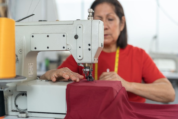 Focus op een naaimachine in een werkplaats terwijl een vrouw aan het werk is