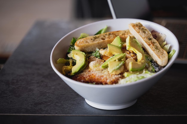 Focus op gemengde salade met sla kip avocado parmezaanse kaas en geroosterd brood witte kom