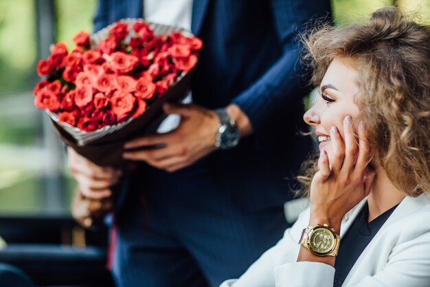 Focus op groot rood boeket rozen, blonde vrouw die naar cadeau kijkt, tijd viert