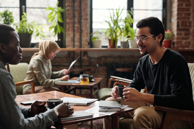 Focus op jonge zakenman met kopje thee in gesprek met collega