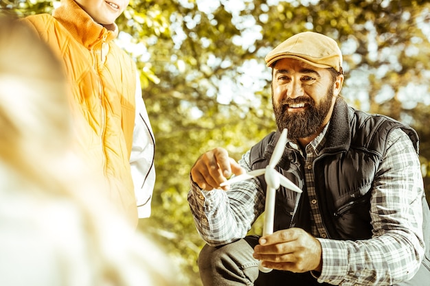 Focus op leraar die een student op een goede dag een windmolen in het bos laat zien