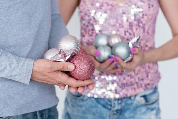 focus op man met handvol rose goud glitter kerstballen. vrouw in de holding zilveren bollen.