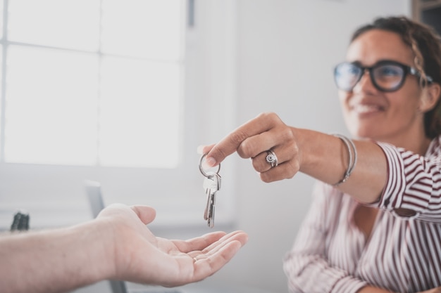 Focus op sleutelbos van huis flat appartement in de hand van lachende vrouw wazig portret