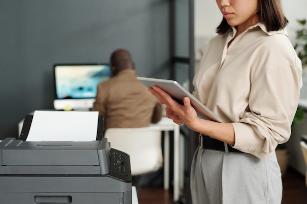 Focus op tablet vastgehouden door jonge elegante zakenvrouw computergebruik op kantoor