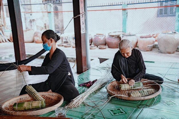 Focus oude vrouw met traditionele Vietnamese kleding oa ba ba Het maken van inpakpapier Tet Cake het Vietnamese nieuwe maanjaar Tet eten buiten door handen