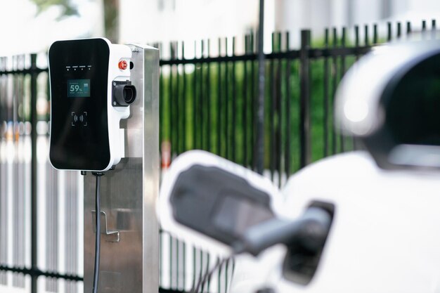 バック グラウンドでぼやけた EV 車とプログレッシブ公共充電ステーションに焦点を当てる