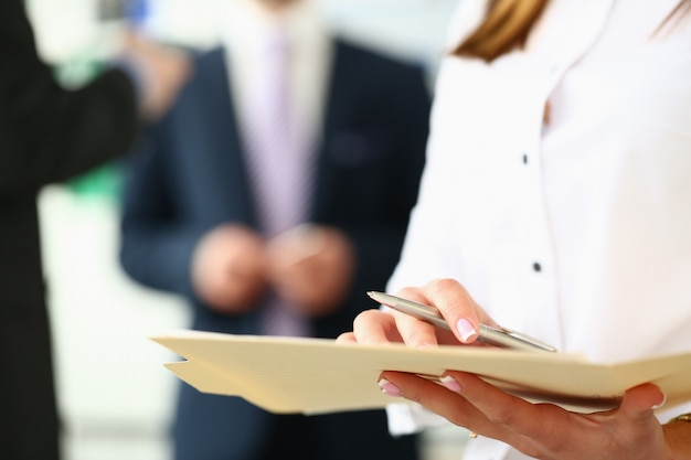 Focus on secretary with pretty manicure inspecting important business contract with concentration in modern office.