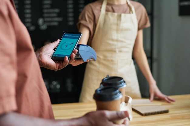 Focus on smartphone held by mature man during contactless payment