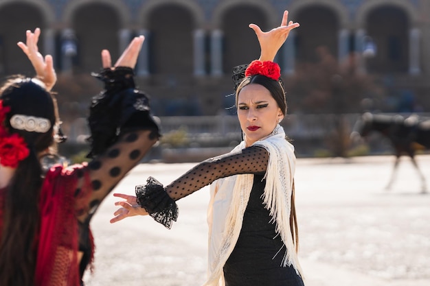 Focus on a spanish woman dancing flamenco in front of other woman outdoors