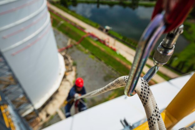 Focus top view male worker down carabiner rope height tank roof\
knot handrail rope access safety inspection of thickness storage\
tank roof.