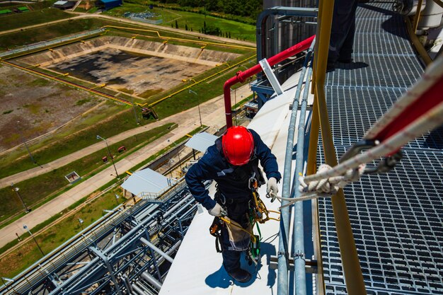 Focus top view male worker down height tank roof knot handrail\
rope access safety inspection of thickness storage tank roof gas\
propane.