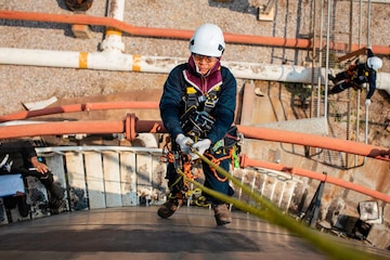 Focus male swing rope worker down height tank roof rope access safety  inspection of thickness storage tank Stock Photo