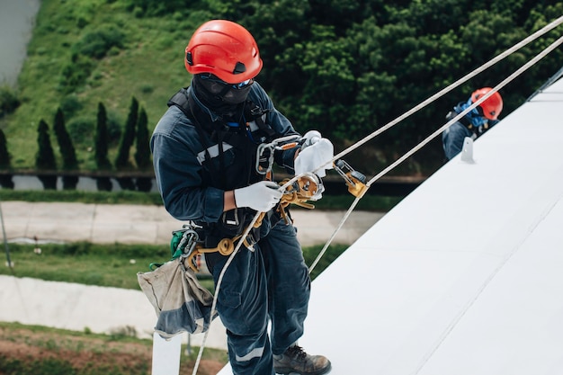 Focus top view male worker down height tank roof rope access\
safety inspection of thickness storage tank gas propane.