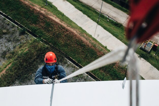 Focus top view male worker down height tank roof rope access\
safety inspection of thickness storage tank gas propane.