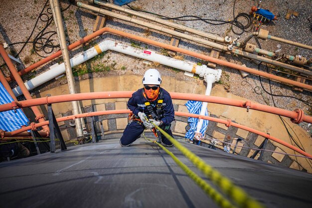 Focus top view male worker down height tank roof rope access safety inspection of thickness storage tank