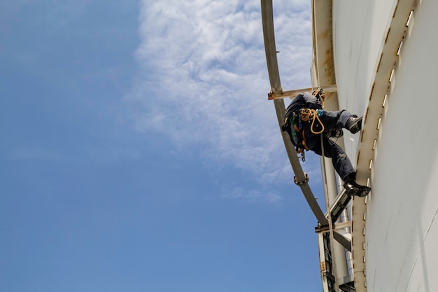 Focus top view male worker down height tank rope access safety inspection of thickness storage oil and gas tank industry