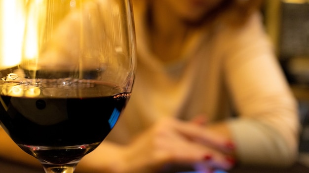Сосредоточьтесь на бокале вина с размытым фоном деловой женщины. Фото высокого качества