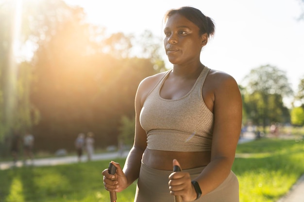 젊은 아프리카계 미국인 여성이 여름에 공원에서 노르 산책을 하는 것에 초점을 맞추고 있습니다.