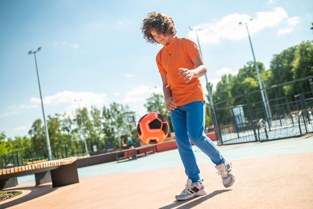 Photo focused adolescent practicing a ball kick technique