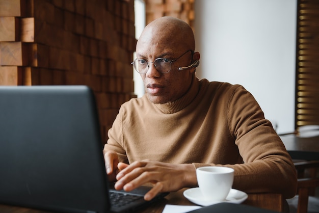 Focused african man wearing headphones watching webinar training making notes