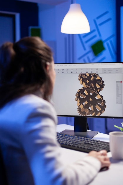 Focused architect working at new project using computer doing gear prototype late at night sitting at desk in start-up office