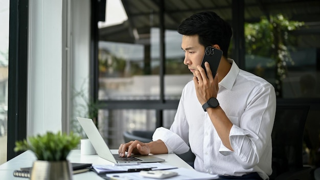 Focused Asian businessman talking on the phone dealing business over the phone