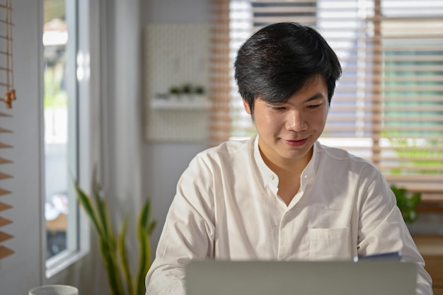 Focused Asian businessman working on his business tasks on laptop in his modern office