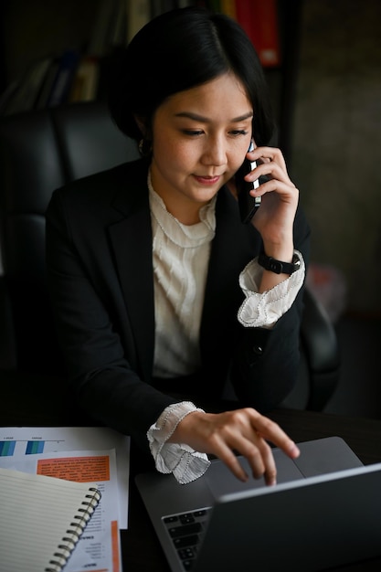 Focused Asian businesswoman is having a formal business phone call at her desk