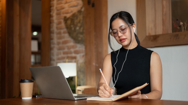 Сосредоточенная азиатская деловая женщина проводит онлайн-встречу или учится онлайн, сидя в кафе.