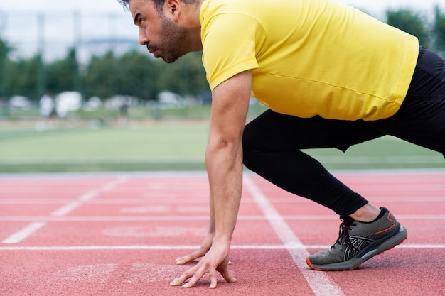 Focused athlete in a low start position bracing for a sprint on the vibrant red rubberized track