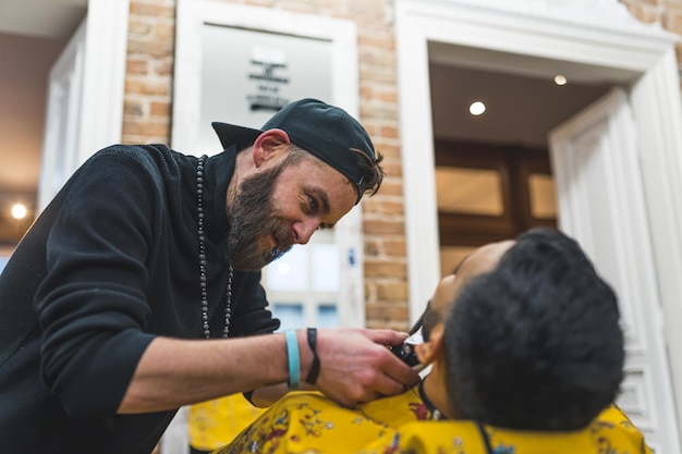 Focused barber trimming facial hair of his indian client in a modern barbershop