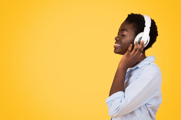 A focused black woman student wearing headphones immersed in her studies or music