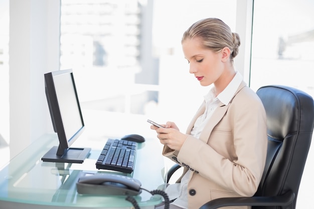 Focused blonde businesswoman text messaging