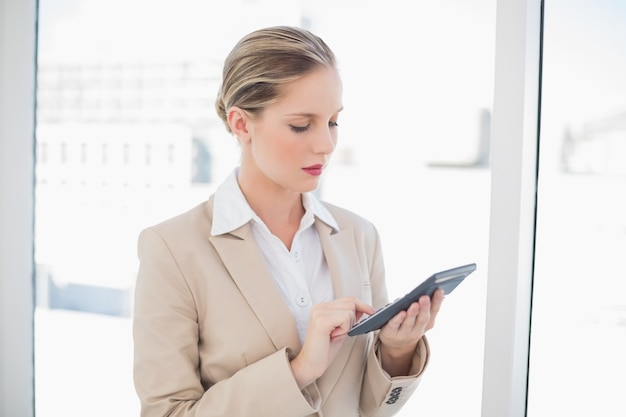 Focused blonde businesswoman using calculator