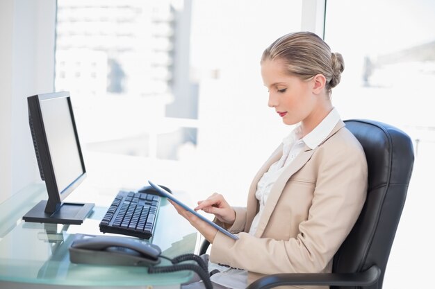 Focused blonde businesswoman using tablet