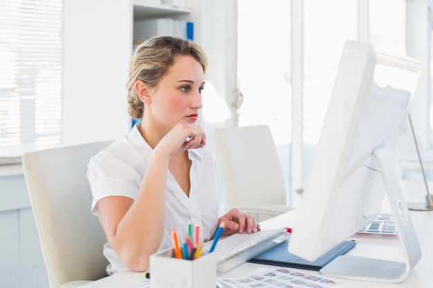 Focused blonde editor working at her desk 