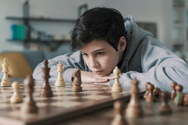 Focused boy playing chess at home