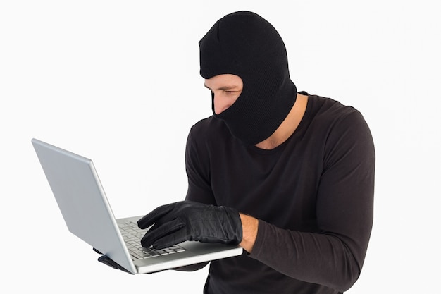 Focused burglar standing holding laptop